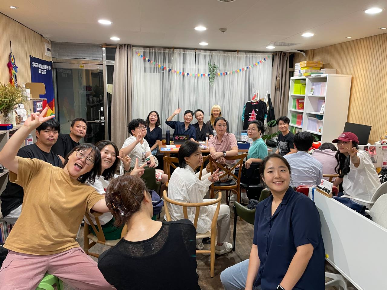 사진 설명 시작. 셰어 사무실에 열여덟 명의 사람들이 모여 앉아있다. 사진 설명 끝.